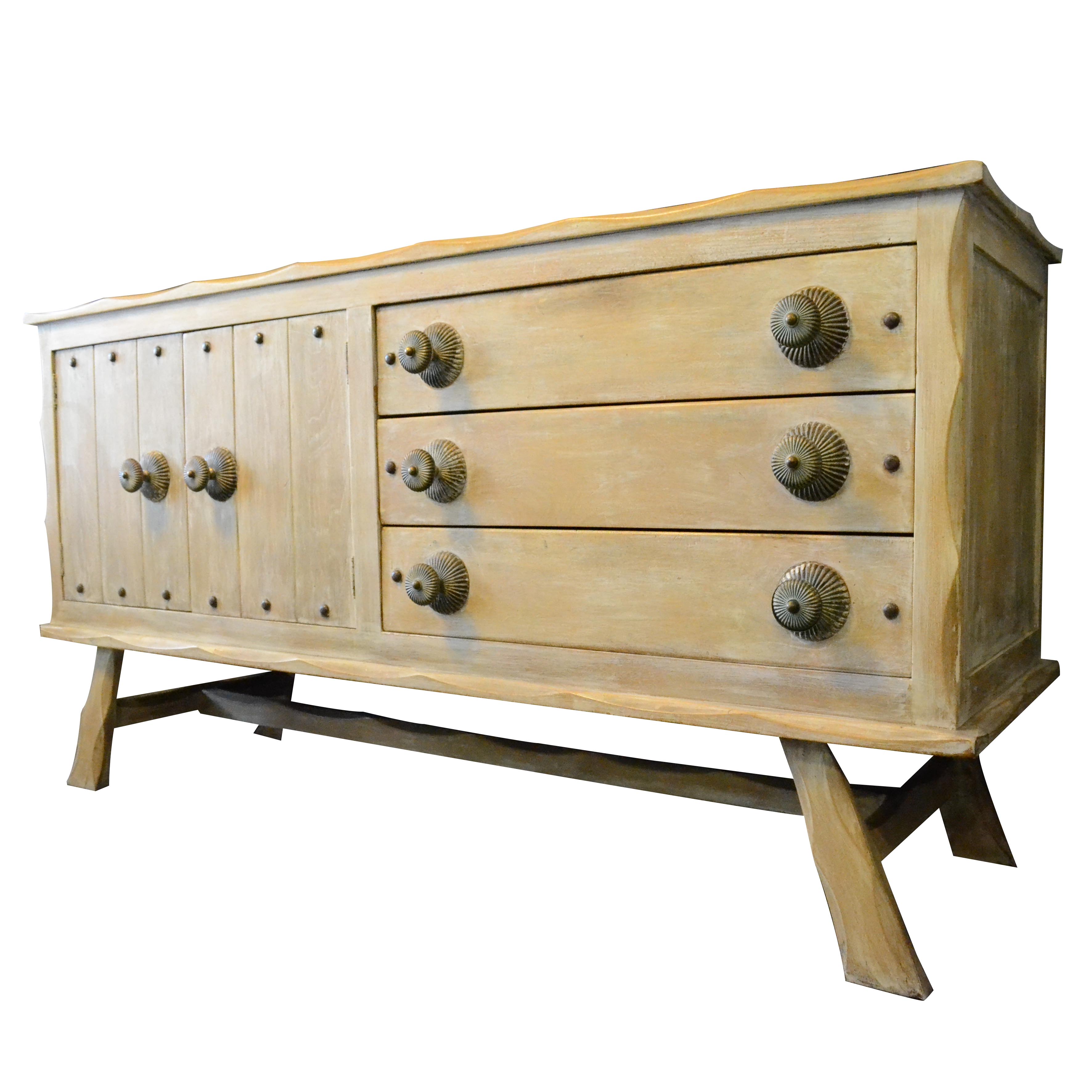 Cómoda elaborada en madera blanqueada con 2 puertas, 3 cajones y tiradores de bronce patinados.