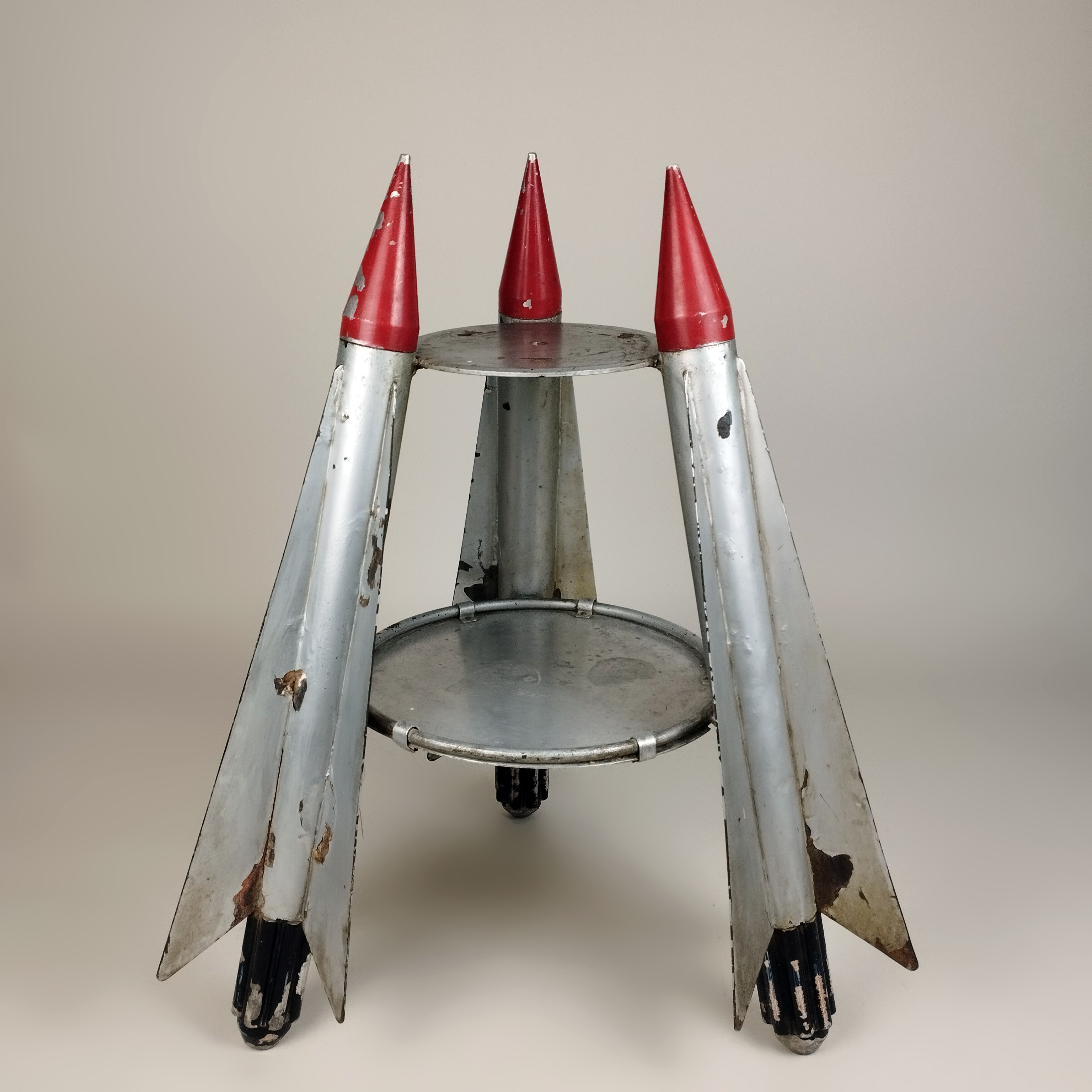 Mesa auxiliar en acero con soportes en forma de cohetes