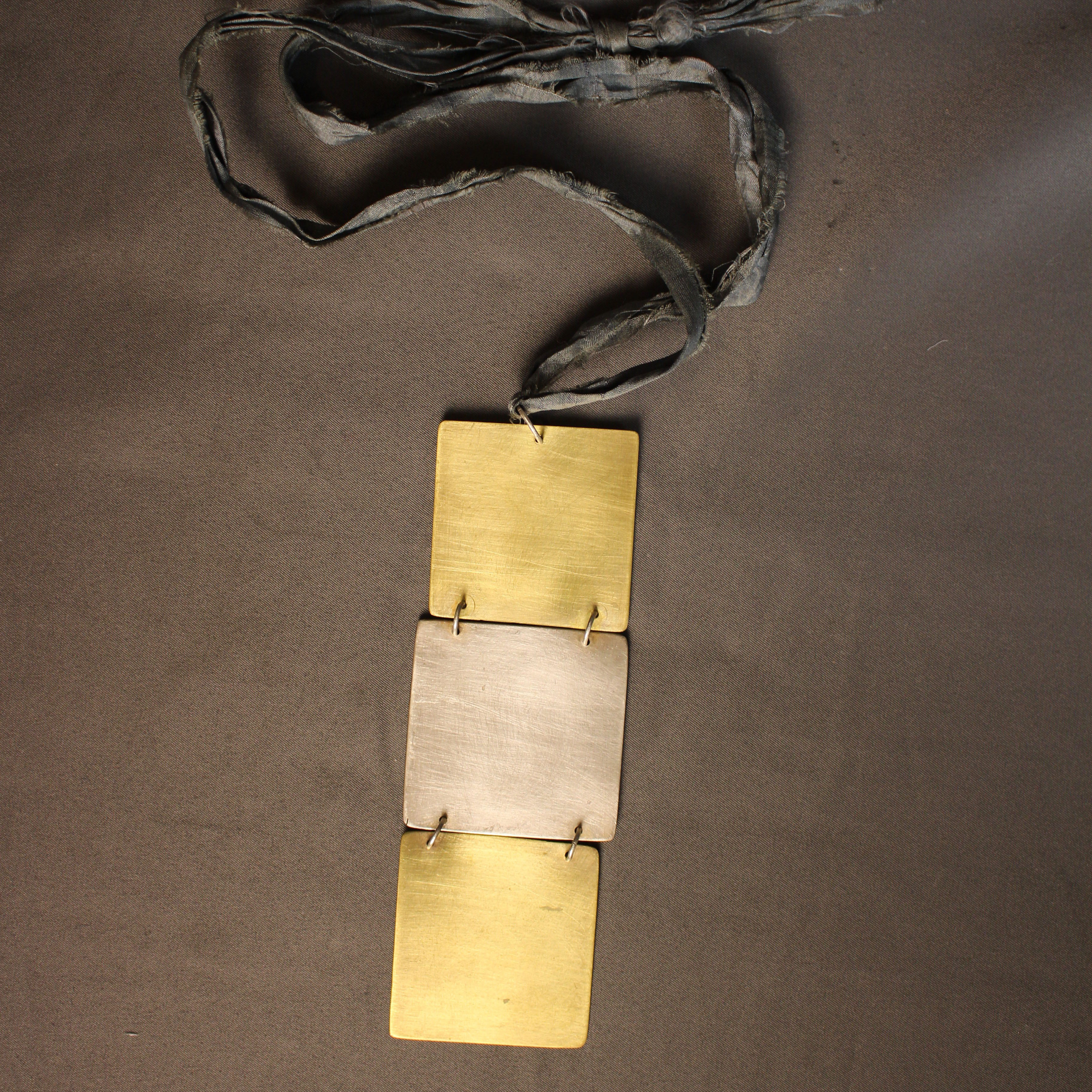 María José de Simón. Collar de latón y plata .925 con listón de seda